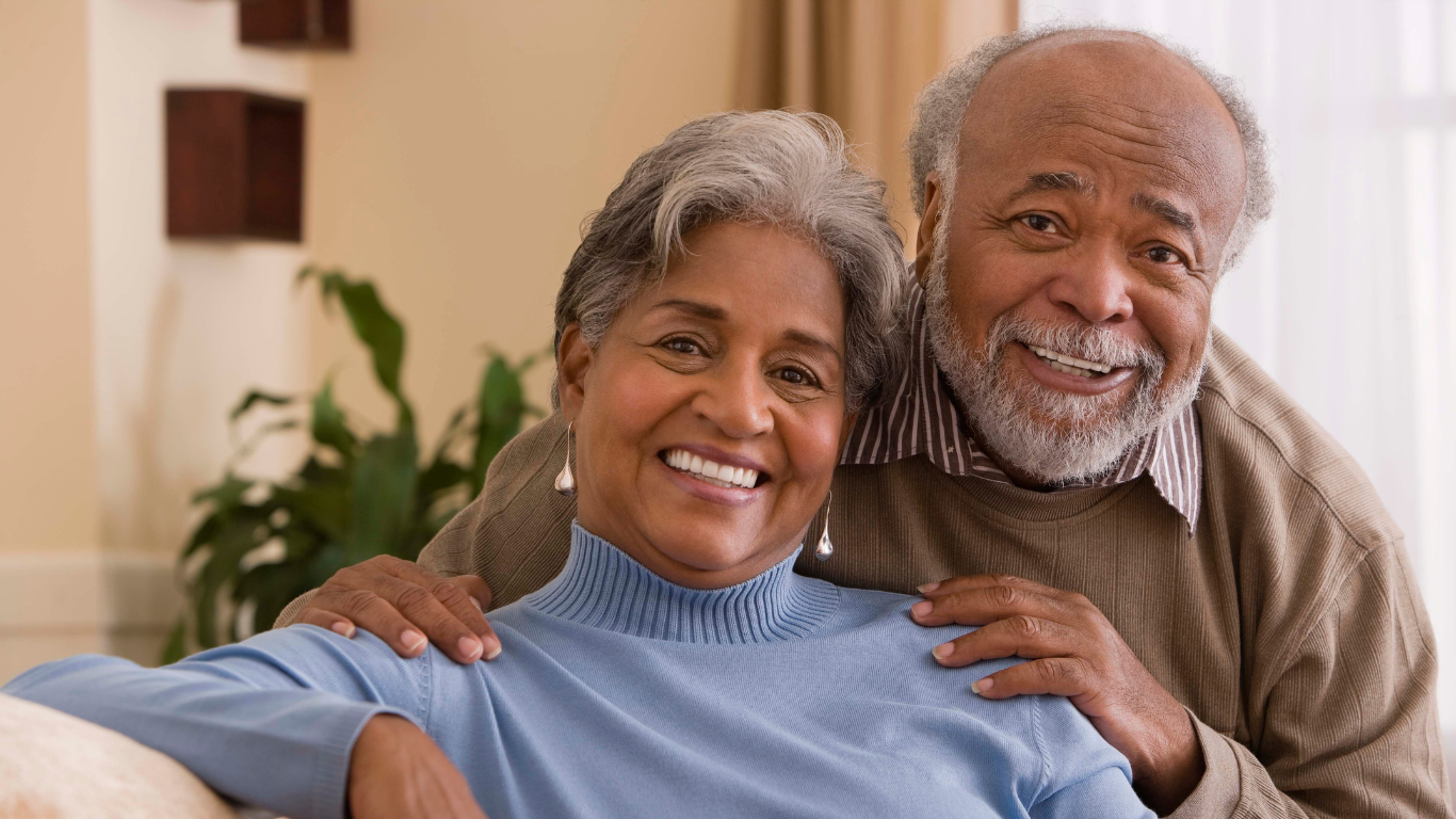 Senior couple smiling while sitting on couch